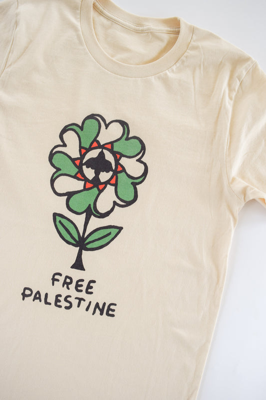 a flower, in green, red, white, and black, with heart shaped pedals and a bird flying upward at the center of the flower. text underneath reads, "free palestine"